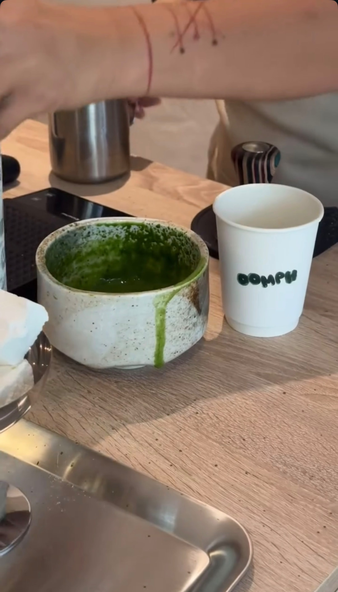 matcha whisked in a stoneware bowl beside an oomph cup